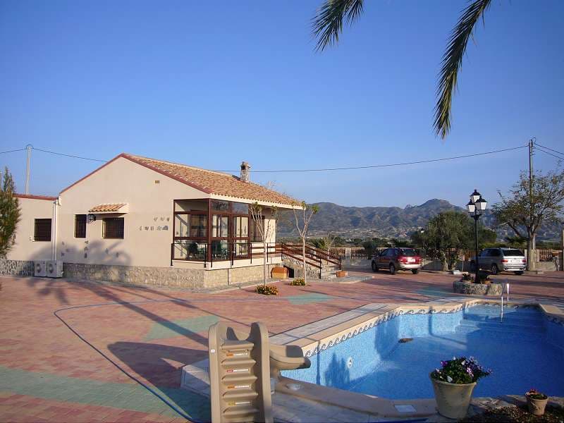 This is a very well finished villa located in a rural location with stunning 360 degree views! If you are looking for low maintenance property that is well finished then this is the villa for you. The villa offers 3 bedrooms and 3 bathrooms on a fenced and gated plot. The master bedroom is large with a separate dressing room and ensuite bathroom. The hallway is also large enough to create or accommodate an office area. The kitchen is well finished with a large utility and dispenser.  Outside the plot is divided into two parts. One half is mono blocked creating a lovely low maintenance area within which there is a an outside kitchen, BBQ, bread/pizza oven and covered setting area. The garden is planted with mature trees and plants and surround a lovely swimming pool with slide. There is also ornate garden lights scattered around the grounds.The house is well finished with lots of extras such as ducted Air Con unit, wired for central music system around the house, electric radiators, glazed porch, ceiling fans, security grills, dressing rooms, utility rooms with all the white goods, etc.We are specialists in the Costa Blanca and Costa Calida specialising in the Alicante and Murcia Inland regions with a particular emphasis on Elda, Pinoso, Aspe, Elche and surrounding areas. We are an established, well known and trusted company that has built a solid reputation amongst buyers and sellers since we began trading in 2004. We offer a complete service with no hidden charges or surprises, starting with sourcing the property, right through to completion, and an unrivalled after sales service which includes property management, building services, and general help and advice to make your new house a home. With a portfolio of well over 1400 properties for sale, we are confident that we can help, so just let us know your preferred property, budget and location, and we will do the rest.