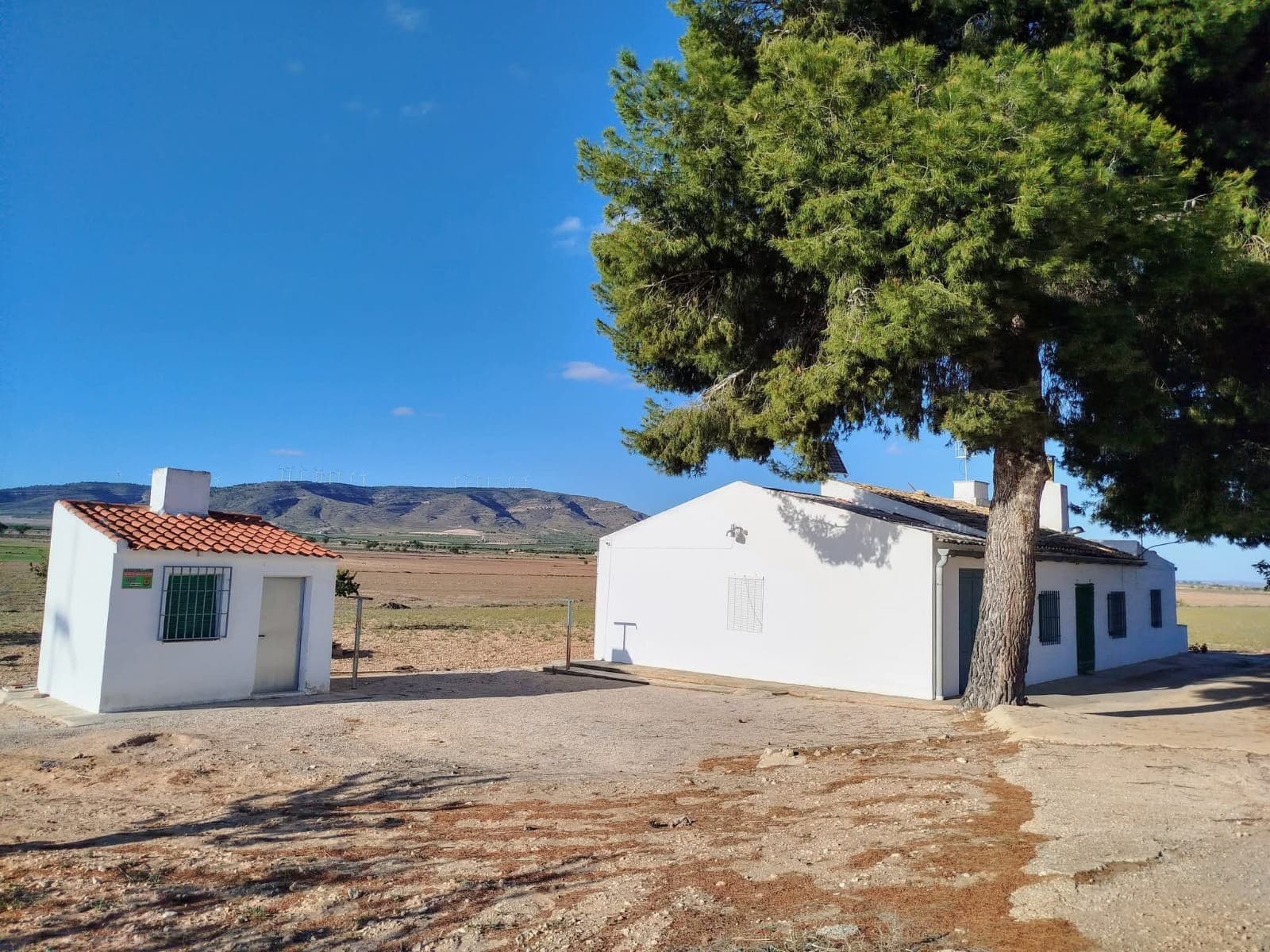 Discover this detached country house located in the serene rural area of Yecla, 9 km from the town. This single-story home spans 100 m² and features 3 bedrooms, a bathroom, a cosy salon complete with a fireplace, a kitchen, and a garage. The house is ready to move in, and could be expanded.This property is off-grid, equipped with solar panels, a wind turbine, and batteries, ensuring sustainable, independent living. The property features expansive land of 55,000 m² (split in 3 parcels), with its own vineyard in full production, it's equipped with irrigation water, allowing extensive agriculture or landscaping projects. Additionally, there is a deposit that can be transformed into a swimming pool.Enjoy the privacy and tranquility, with no neighbours close, yet with a comfortable, asphalted access. Surrounded by trees, the house offers ample shade and a tranquil atmosphere, making it an ideal retreat. This villa is available at a great price, providing an excellent opportunity for further development in form of new constructions or touristic or agricultural business. Discover the numerous possibilities!About the area: Yecla is renowned for its wine production, historical landmarks, and vibrant local culture. The surrounding natural landscapes provide opportunities for outdoor activities, while the town itself offers all necessary services, including schools, shops, and restaurants. This property combines the tranquility of countryside living with easy access to modern amenities.About us: We have a large portfolio of properties in the Costa Blanca and Costa Calida areas, specialising in country properties, villas, fincas, building plots and design and build options in the Alicante and Murcia regions with a particular emphasis on Elda, Monovar, Pinoso, Sax, Villena, Aspe, Fortuna, Albacete and many more surrounding areas. We have been established since 2004 and have decades of experience between the team which we bring to bear to help you find and secure your new dream home. We help you every step of the way to make sure your purchase in Spain is safe and hassle free. We are not here to sell you a property, we are here to help you realise your dream and find what is right for you. With us you are in the safest hands. Contact us now to have a no obligation chat about how you too can realise your dreams.
