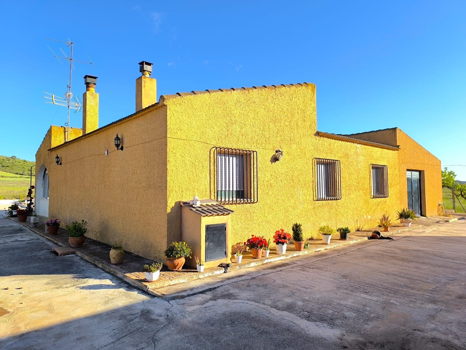 Charming detached country house offering peace, privacy, and beautiful mountain views, set on a plot of over 24,000 m², of which approximately 1,200 m² is fenced. Located just 10 minutes from town, the property is accessed via a tarmac road with only the last 150 metres being a dirt track.The house provides 140 m² of comfortable living space and includes 4 bedrooms, 1 bathroom, a spacious and cosy living room with a pellet burner, and a semi-open kitchen with pantry. A bright, walled terrace creates a wonderful space to relax throughout the year. The property is sold fully furnished, including appliances, and is ready to move into immediately. The house is solidly built, very well maintained, and benefits from insulated walls and roof.An additional room with independent access, currently used as a dining room, offers excellent potential to create a guest annex or separate accommodation. It is connected with a 70 m² garage/workshop. The house operates on solar system (2.4 kW of panels with 7 kWh of batteries), its capacity is enough for a seasonal use. There's no mains electricity available.Outside, you'll find a 70 m² carport/storage area, a dog kennel with dog house, and a large 80,000-litre concrete swimming pool with a neighbouring outdoor shower building. Extending the house is possible.The surrounding land is partially planted with almonds, olive trees, and fruit trees, while most of it remains fallow, making it ideal for growing crops, planting additional trees, keeping horses, or creating a self-sufficient lifestyle project.With no close neighbours, complete tranquility, mains irrigation water with 3 water rights, and endless possibilities, this is a rare opportunity to enjoy authentic countryside living in total privacy.About the area: Yecla is a charming and historic town of app. 35000 inhabitants, located in the region of Murcia. It is renowned for its award-winning wines, historical landmarks, and vibrant local culture. The surrounding natural landscapes of scenic mountains, vineyards and almond groves provide opportunities for outdoor activities, while the town itself offers all necessary services, including hospital, schools, shops, restaurants, and other services. With a friendly local community, lively markets, excellent gastronomy, and easy access to nature, Yecla is an ideal location for those seeking authentic Spanish lifestyle - just about an hour from the coast and Alicante airport.About us: We have a large portfolio of properties in the Costa Blanca and Costa Calida areas, specialising in country properties, villas, fincas, building plots and design and build options in the Alicante and Murcia regions with a particular emphasis on Yecla, Novelda, Elda, Monovar, Pinoso, Sax, Villena, Aspe, Fortuna, Jumilla, Abanilla, and many more surrounding areas. We have been established since 2004 and have decades of experience between the team which we bring to bear to help you find and secure your new dream home. We help you every step of the way to make sure your purchase in Spain is safe and hassle free. We are not here to sell you a property, we are here to help you realise your dream and find what is right for you. With us you are in the safest hands. Contact us now to have a no obligation chat about how you too can realise your dreams.